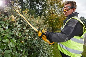 DEWALT DCM563PB-GB 18V XR Hedge Trimmer in use.